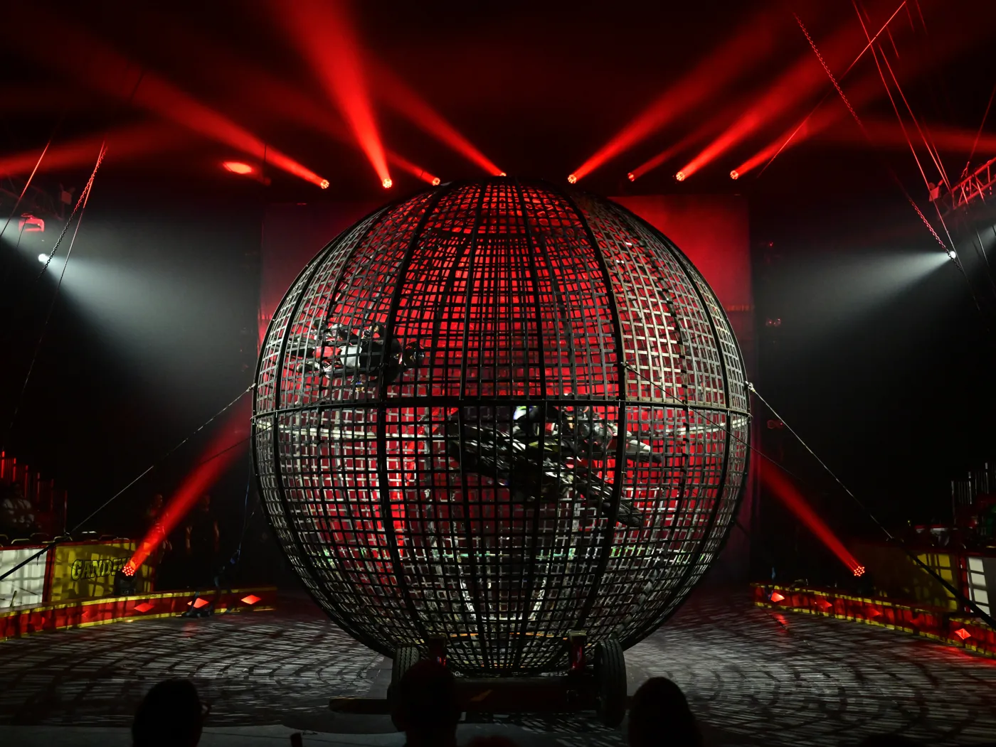 A motorbike rider inside a steel globe under red stage lights