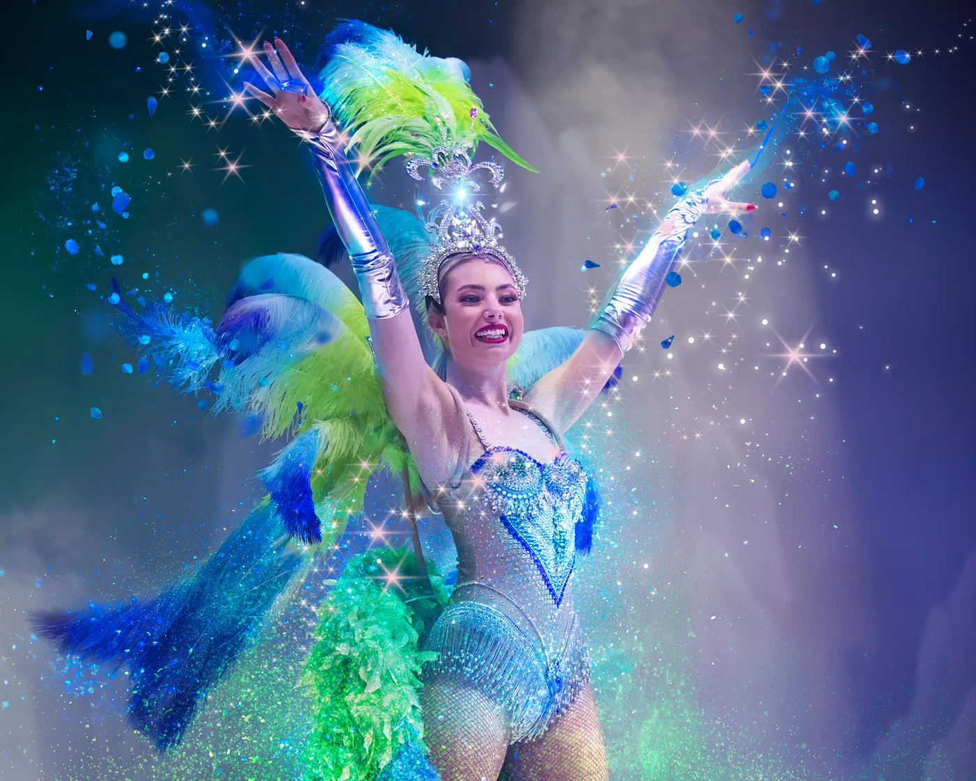 A showgirl in a jewelled costume and green feathered headdress with arms raised